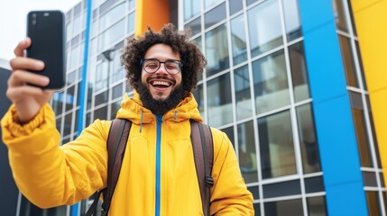 Young man taking selfie outside modern building urban setting lifestyle photography cheerful expression bright colors