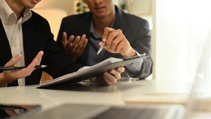 Cropped shot business advisor explaining the contract, offering it for the client to sign.