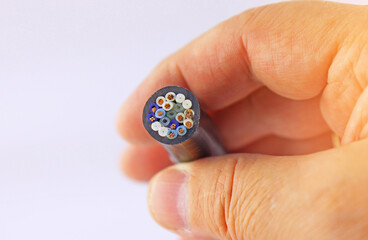 The hand is holding a copper electrical insulated mounting cable. 