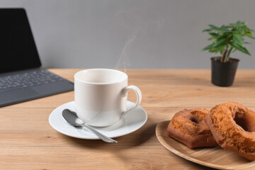 湯気の立つ温かいコーヒーとドーナツでコーヒーブレイク