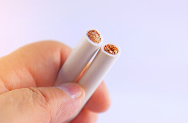 The hand is holding a copper electrical insulated mounting cable. 