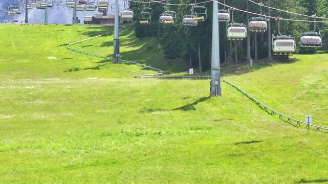 Toboggan track winds through green slopes under cable cars on a sunny day in Haunold mountain