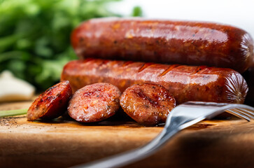 A stack of seared smoked sausages with glistening, crispy edges on a wooden cutting board, their caramelized exteriors revealing a perfect balance of smoky and savory flavors
