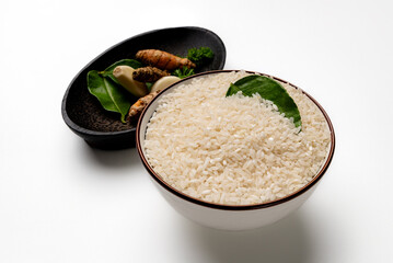 A bowl of raw white rice, with a variety of spices in a wooden bowl, Asian culinary ingredients