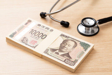 机に置かれた聴診器と100万円