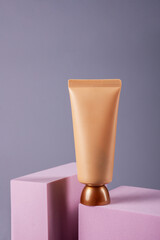 Plastic tube for cream or lotion. Skin care or sunscreen cosmetic with stylish props on grey background.