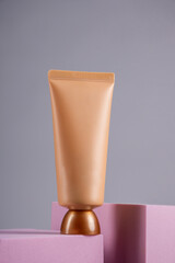 Plastic tube for cream or lotion. Skin care or sunscreen cosmetic with stylish props on grey background.