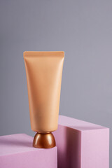 Plastic tube for cream or lotion. Skin care or sunscreen cosmetic with stylish props on grey background.