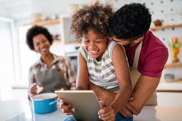 Happy african family having fun with device at home. Black parents and child using digital tablet