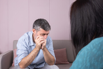 Obraz premium A patient in therapy, pensively looking to the side and sitting facing his psychotherapist, with his back turned. Concept of mental health and therapy