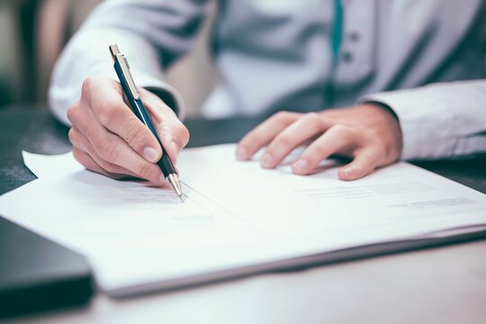 This image features a doctor examining clinical guidelines in a sterile setting, highlighting the importance of medical standards for patient safety and effective treatment.
