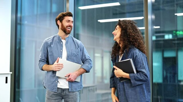 Two casually dressed business people discuss strategy in a modern office. Teamwork and collaboration are evident as they give a high five expressing their success.