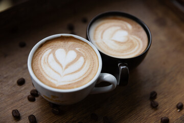 Two cups of latte with beautiful heart-shaped foam art sit side by side on a rustic wooden table, highlighting their creamy textures and creating a cozy and inviting coffee experience