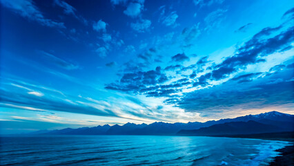 Blue sky meeting the calm ocean with clouds reflecting sunlight on a summer day