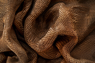 Fototapeta premium Textured Brown Snake Skin Brown Mocha Mousse Color Fabric Background, Luxurious Patterned Material with Shimmering Details and Rich Tones