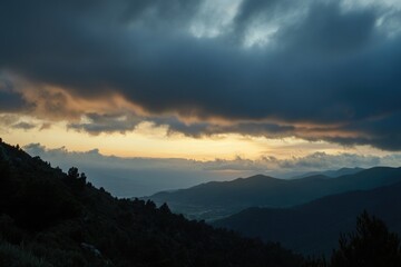 Fototapeta premium A beautiful sunset scene over a mountain range with dark clouds in the sky
