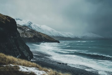 A serene coastal scene featuring a majestic mountain range covered in snow, set against a backdrop of clear blue water