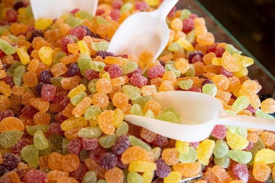 Grand pr&eacute;sentoir de petits bonbons aux fruits recouverts de sucre. Trois pelles blanches pour pr&eacute;parer les sachets &agrave; peser.
