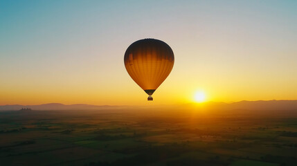 Obraz premium Hot air balloon floats over a picturesque landscape at sunrise with golden hues illuminating the sky and horizon