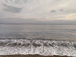 The Silent Shore: A Metaphor of Endless Horizons and Fleeting Waves, Where Pebbled Stillness Meets the Moody Sky, Reflecting a Timeless Serenity Amid the Calm Before the Storm in Nature’s Unspoken.