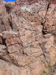 Fototapeta premium Wild red-brown rocks. Summer sunny day. Red granite in nature. Natural mineral background.