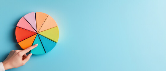 Fototapeta premium hand pointing at colorful pie chart on blue background, illustrating data segments