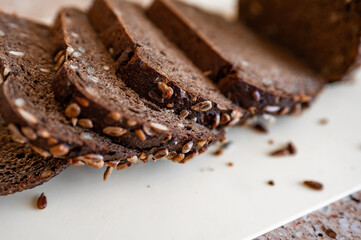 black artisan bread with seeds on a white board