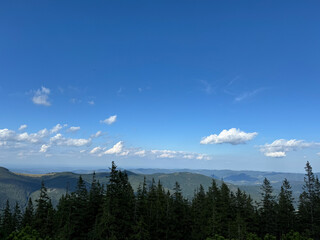 Top view of mountains. Colorful panorama of the mountain, green hills, low clouds, clouds over the mountain. Nature scene of pine trees of Carpathian mountains