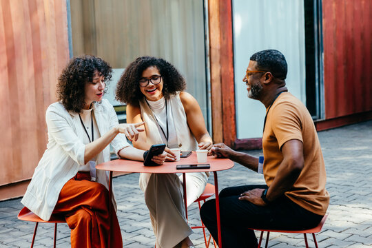 Colleagues enjoying a casual outdoor meeting with coffee and smiles