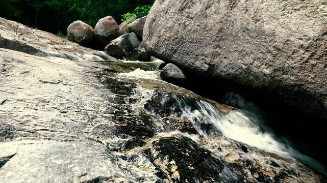 A stream of a mountain river flows under a huge stone in the jungle