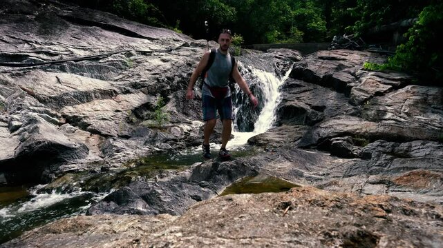 A tourist crosses a mountain stream in the jungle