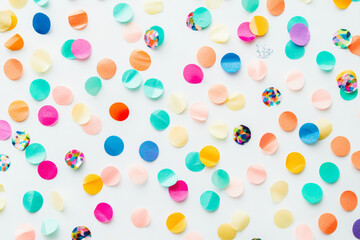 Colorful confetti circles scattered on white background create festive atmosphere