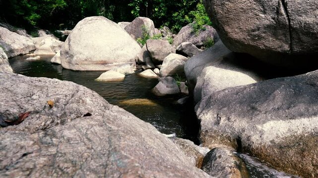 The stream of the mountain river flows between large rocks in the jungle