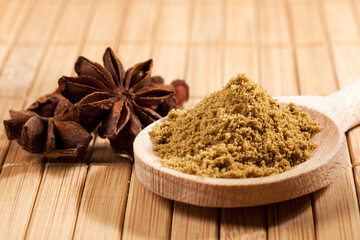Ground anise on wooden spoon, whole star anise in background