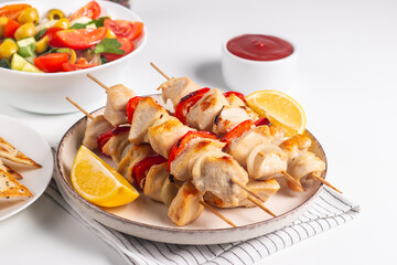 Delicious grilled chicken skewers with capsicum, lemon, salad and ketchup on a plate over the table. Chicken kebab. Healthy food concept.