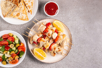 Delicious grilled chicken skewers with capsicum, lemon, salad and ketchup on a plate over the table. Chicken kebab. Healthy food concept.