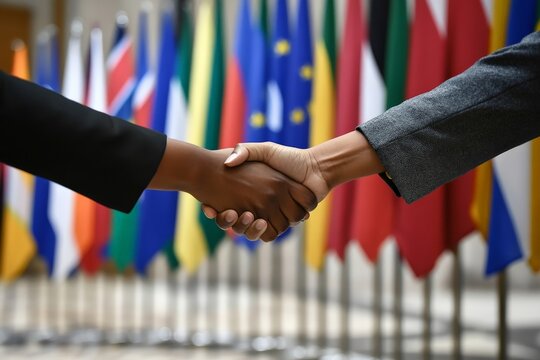 A diverse handshake in the foreground with country flags as the backdrop, representing international cooperation, diversity, and unity across cultures.