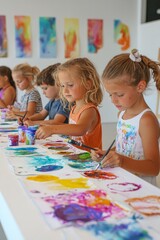 Fototapeta premium Group of young children painting with vibrant watercolors at a clean, white table