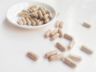 Supplement capsule pills in a small white plate on a white background.
