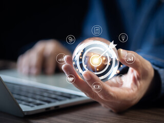 Business startup and target concept. Businessman holding a clear glass ball with icon business and network connection on modern virtual interface. Target and success and business goals..