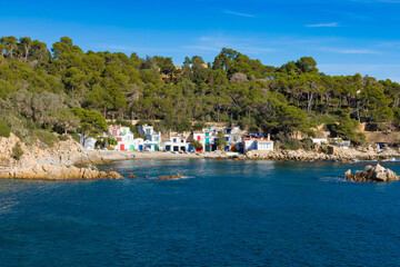 Casitas de pescadores junto al mar, rodeadas de bosque mediterráneo en Cala S'Alger.