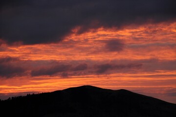 colorful sky at sunrise with a small hill in the foreground