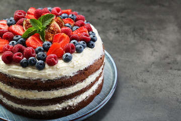 Delicious chocolate sponge cake with berries on grey table, closeup. Space for text