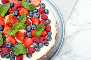Delicious chocolate sponge cake with berries on white marble table, top view