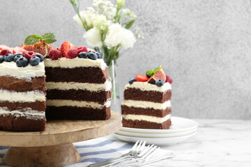 Piece of delicious chocolate sponge cake with berries served on white table