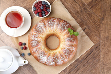 Freshly baked sponge cake, tea and berries on wooden table, top view
