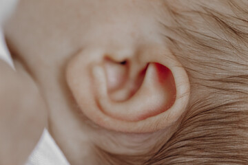 A baby's ear is shown in detail, with the ear lobe and the ear canal visible. Concept of curiosity and wonder, as it captures a moment of exploration and discovery