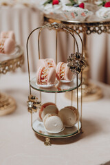 A tray of pastries with a gold stand holding them. The pastries are pink and white