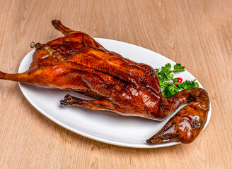 Roasted Goose Whole with coriander served in tray dish isolated on wooden table side view of hong kong food