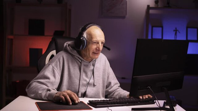 Senior man gamer with headphones streaming broadcasting video game online at night, talking in entertainment atmosphere.